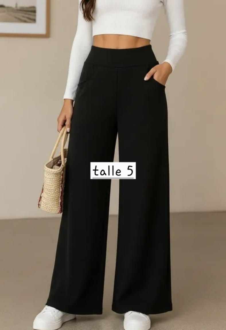 Persona con una blusa blanca y pantalones grises de pierna ancha con las manos en los bolsillos; el texto dice “pantalon darlon tipo sastre talle 4”