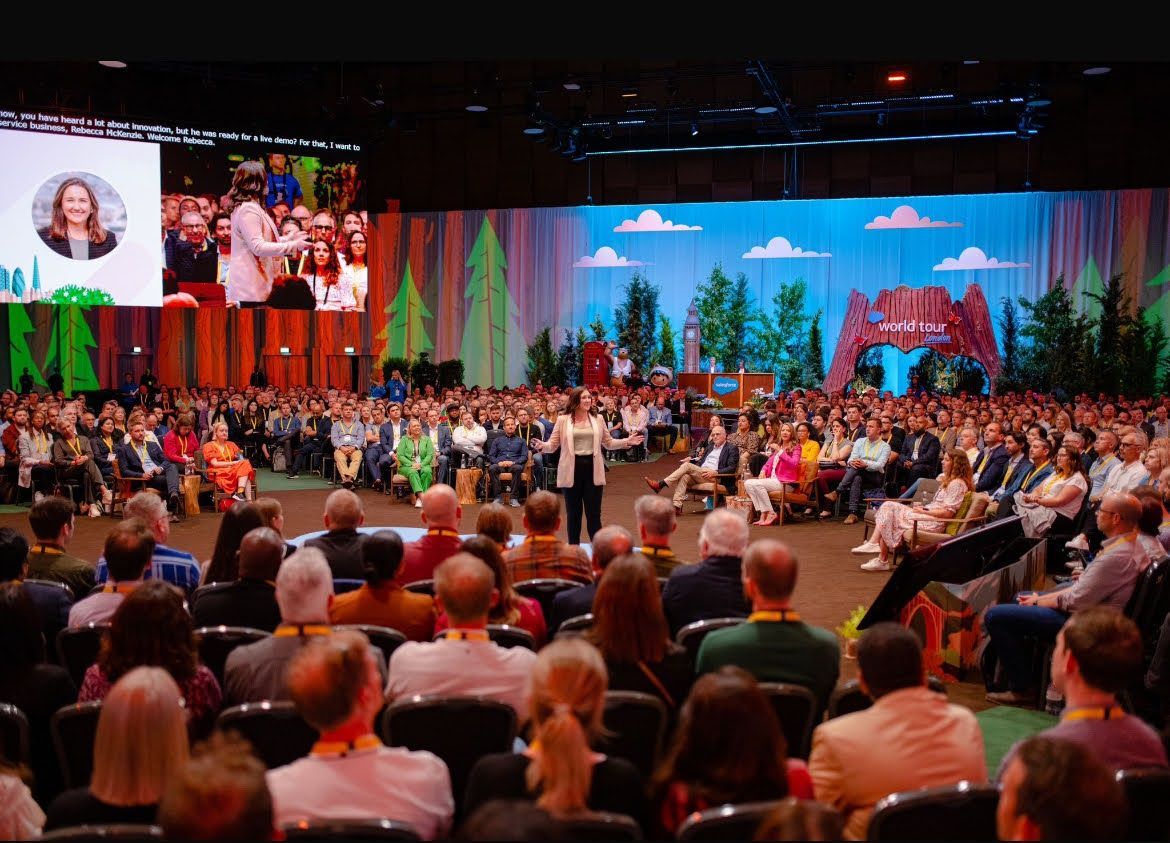 Large conference: Speaker addressing a crowd. Background features a nature-themed backdrop and screen.