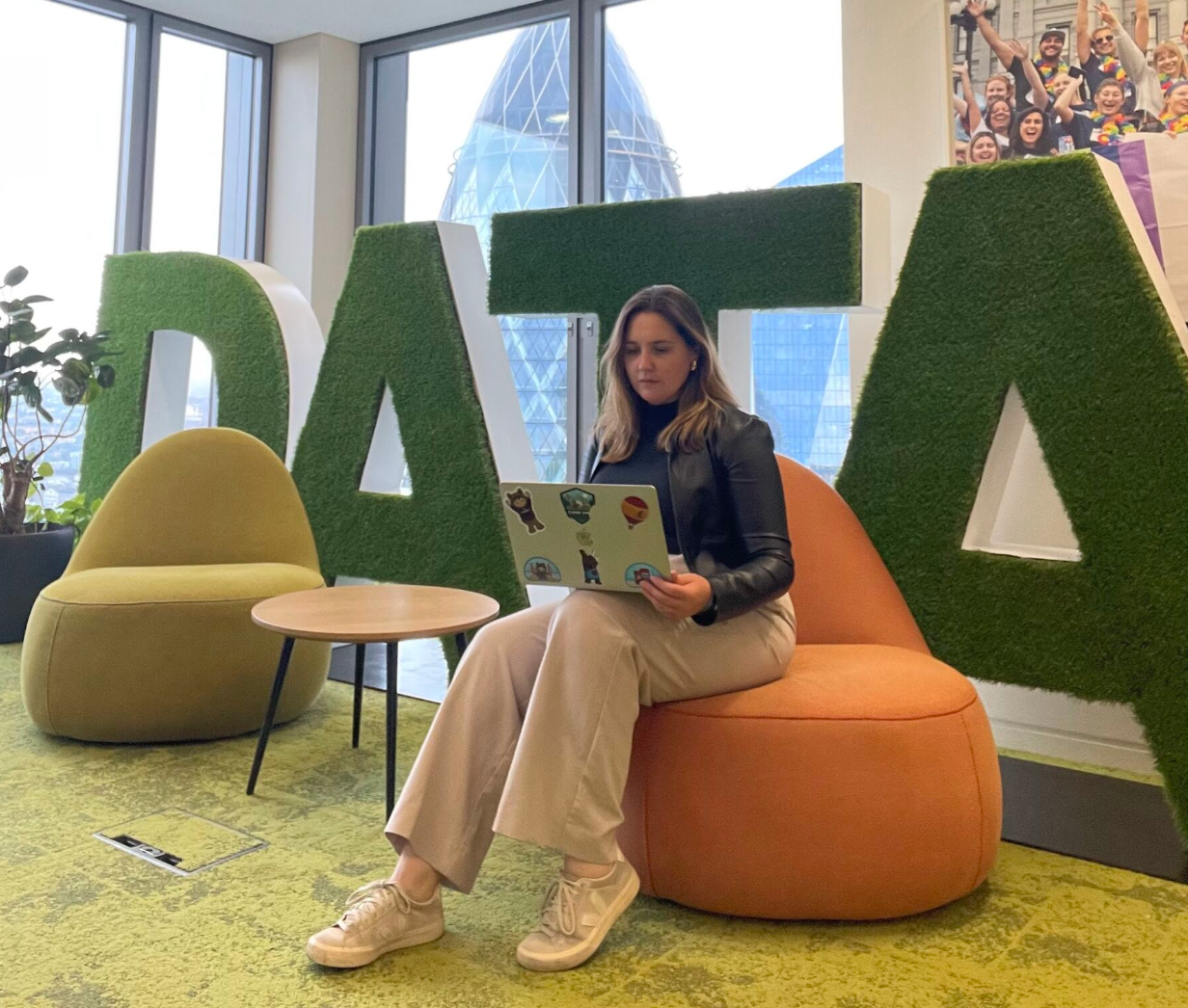 Rebecca sitting on a laptop in front of a sign that says data