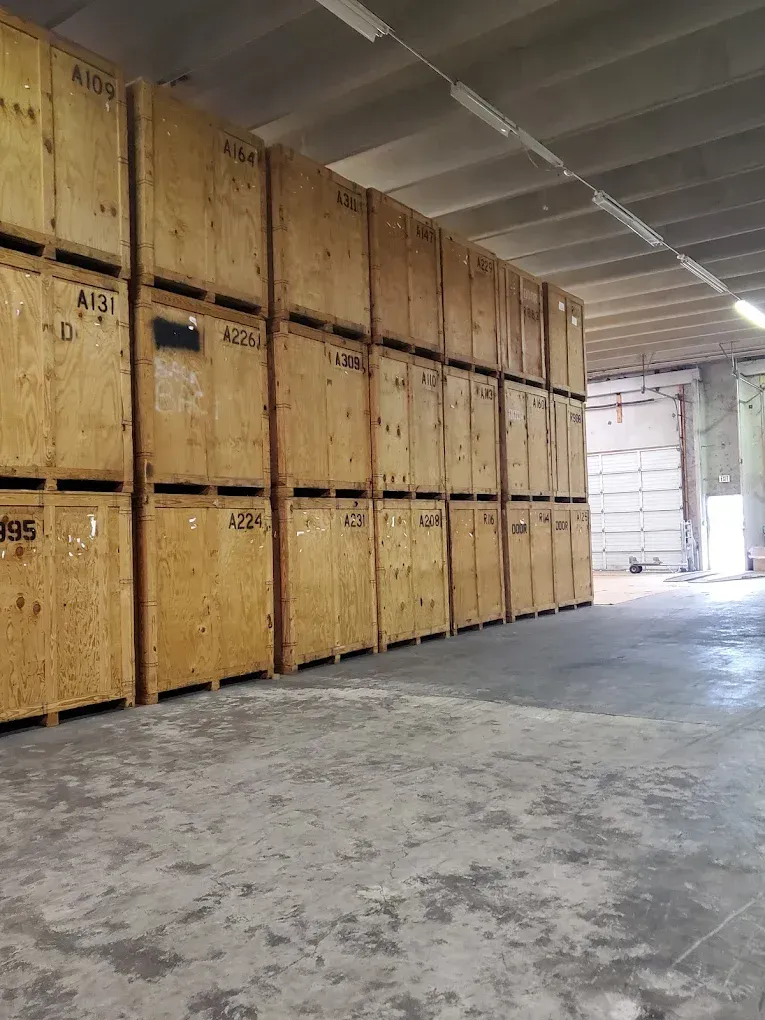 Rows of wooden storage containers stacked inside a large warehouse, with a loading door visible.
