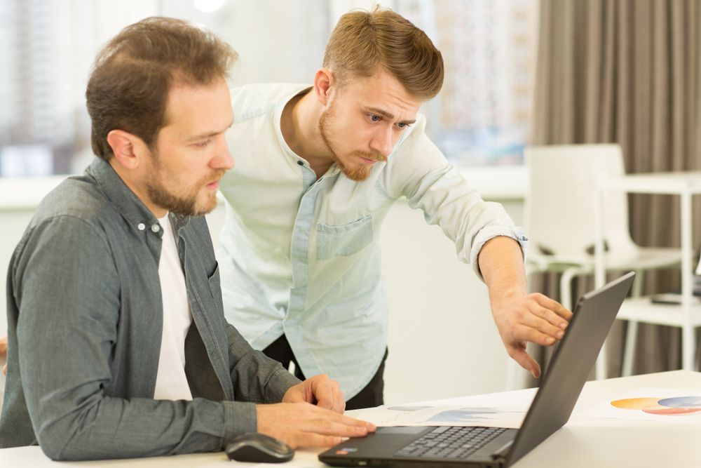 Two Coworkers Reviewing a Laptop Together — Compago Technologies In Cambridge, TAS