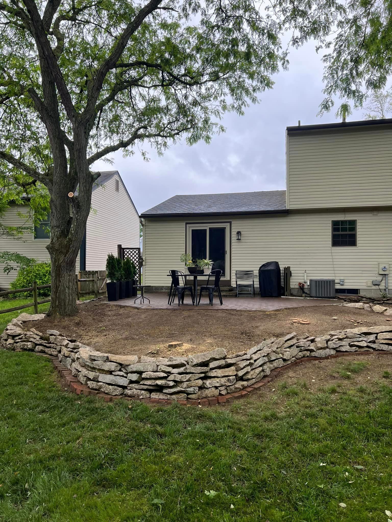 A house with a patio and a stone wall in front of it.