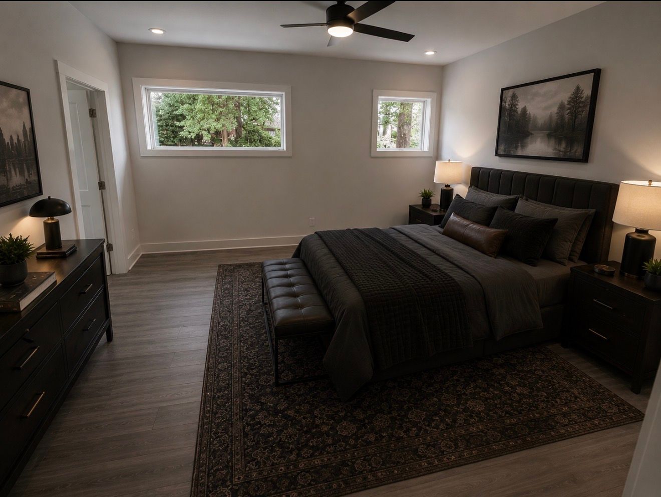 Modern bedroom with dark bedding, rug, ceiling fan, nightstands, and two windows