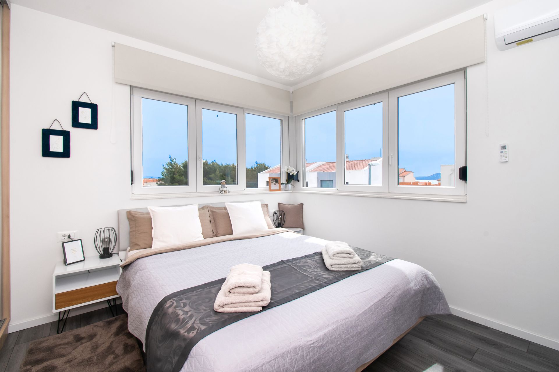 Bedroom with a bed, windows, nightstand, and decor, with a view of the outside.