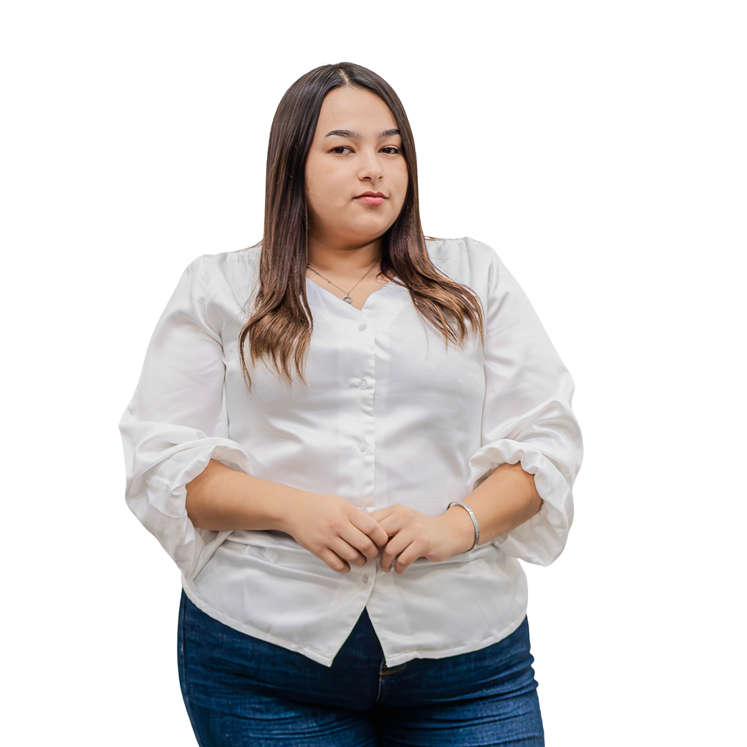 Una mujer con una camisa blanca y jeans azules está parada frente a un fondo blanco.