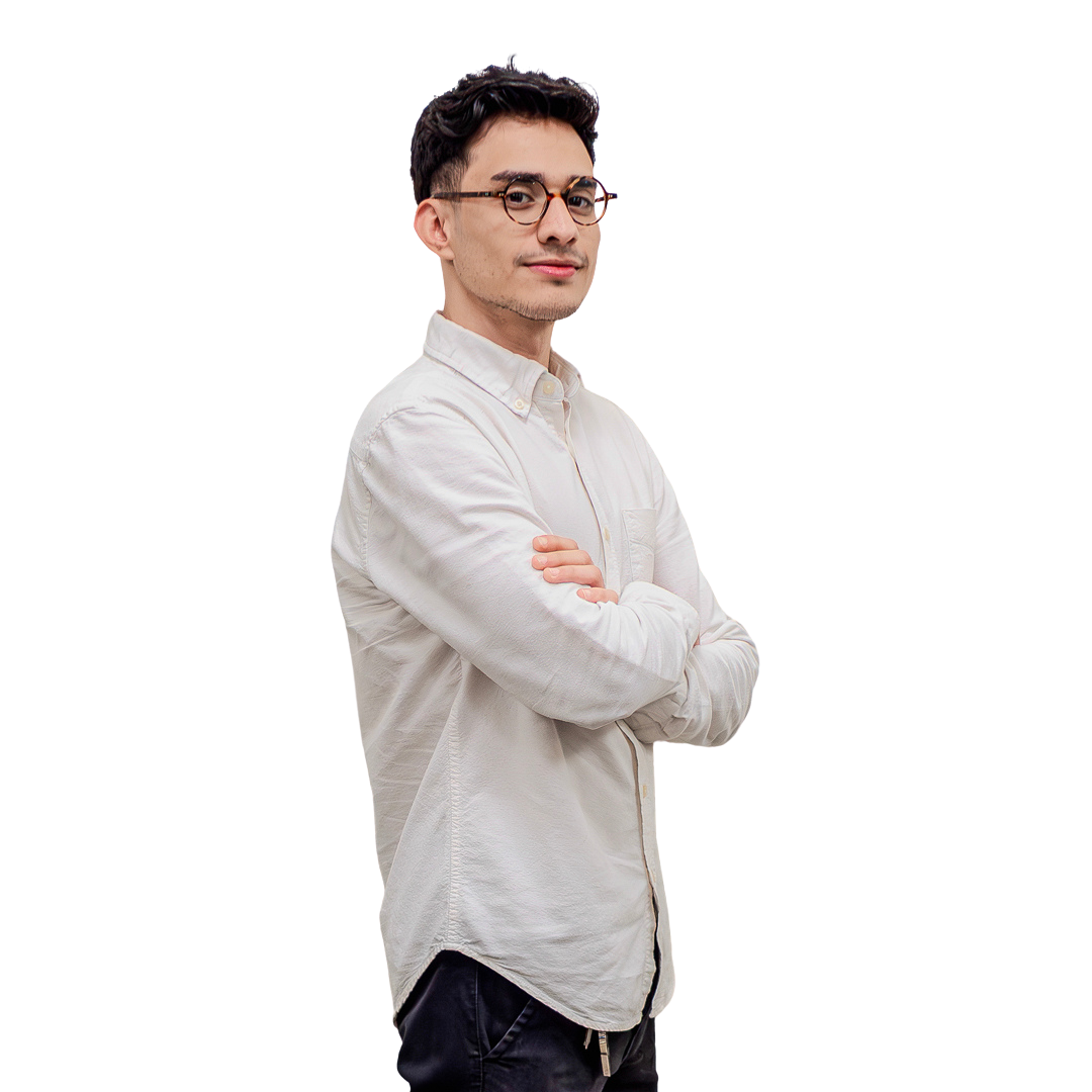 Un hombre que lleva gafas y una camisa blanca está de pie con los brazos cruzados.