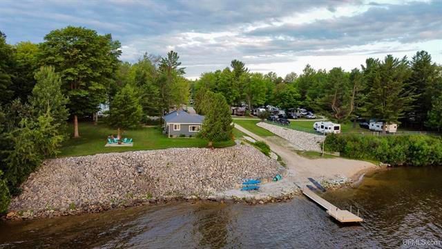 an aerial view of a lake with a dock and a house in the background .