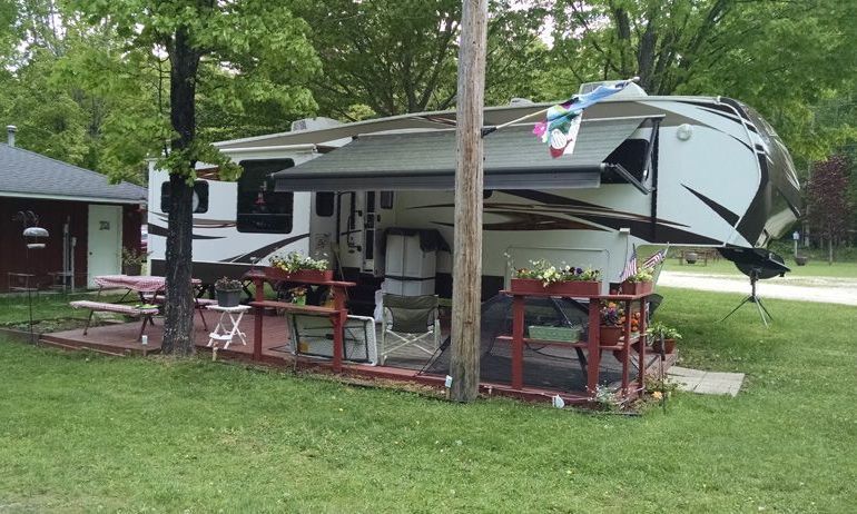 a rv is parked in a grassy area next to a house .