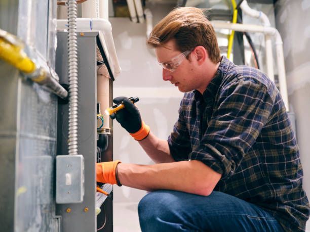 Technician in gloves inspecting electrical control panel with a tool in an industrial facility