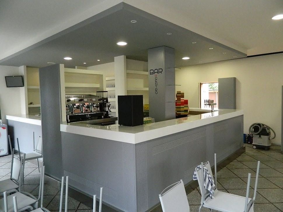 Interno vuoto del bancone di un bar con decorazioni grigie e bianche e faretti a incasso sul soffitto.