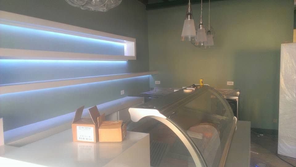 Moderna sala spa con lettino da massaggio, luci a parete blu soffuse e pareti verdi.