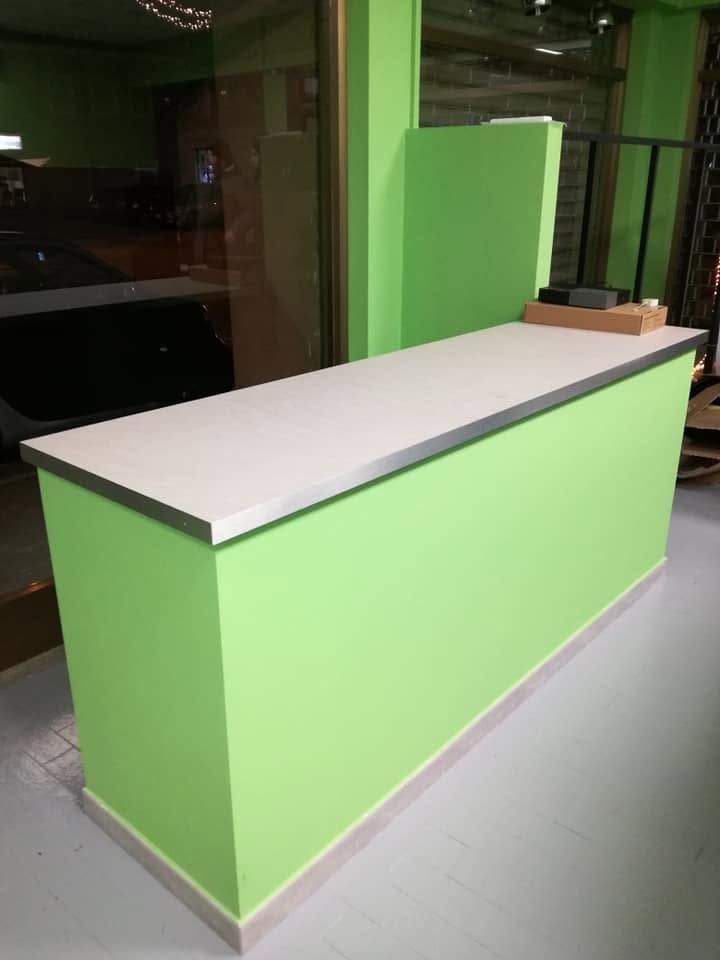 Bancone reception verde con piano bianco in una hall interna