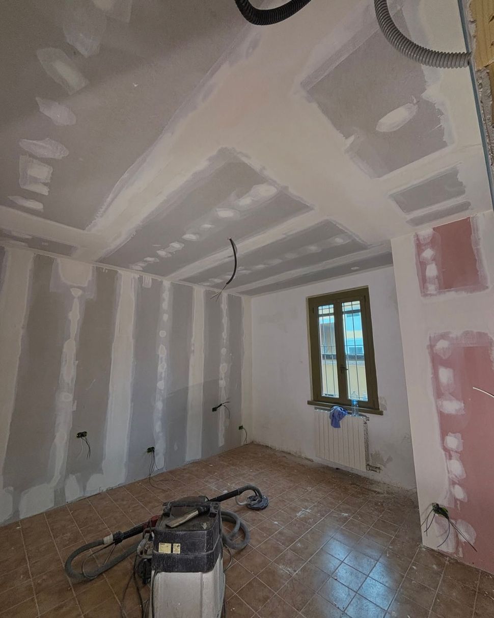 Soggiorno moderno e vuoto con parete d'accento grigia, luci a soffitto blu, ampia finestra e pavimento in legno chiaro.