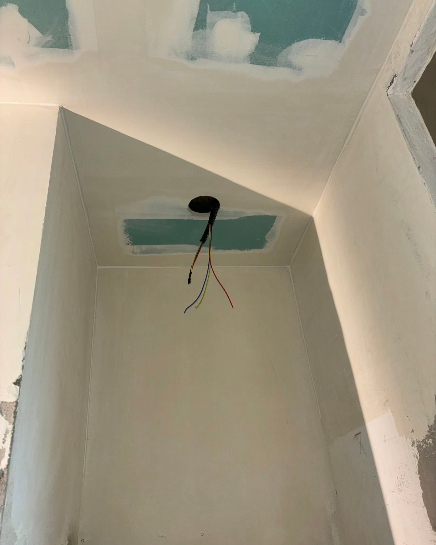 Scatola di derivazione per plafoniera con fili a vista in una stanza bianca in fase di ristrutturazione.