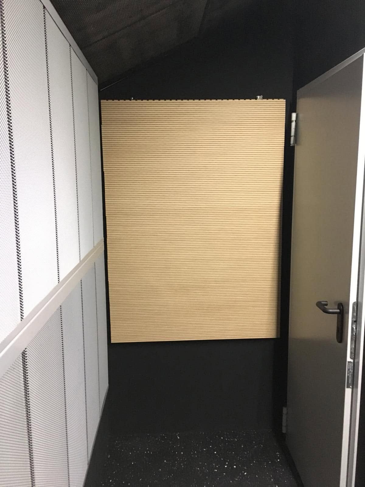 Stretto corridoio con una tenda beige chiusa in fondo, pareti bianche e una porta aperta sulla destra.