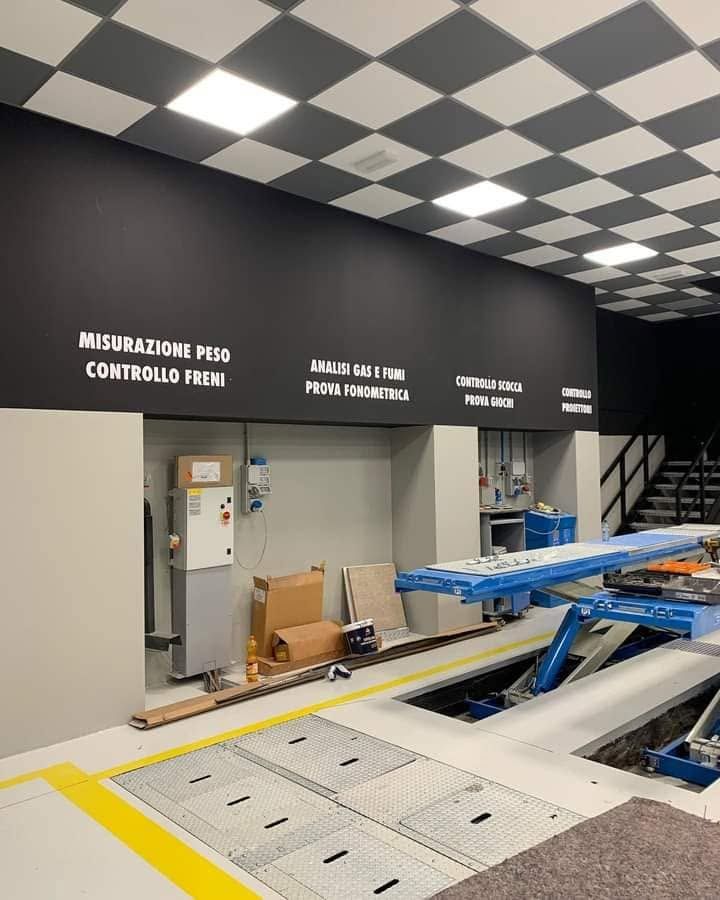 Sala di controllo interna di una fabbrica con soffitto a scacchi bianchi e neri e macchinari blu sul pavimento.