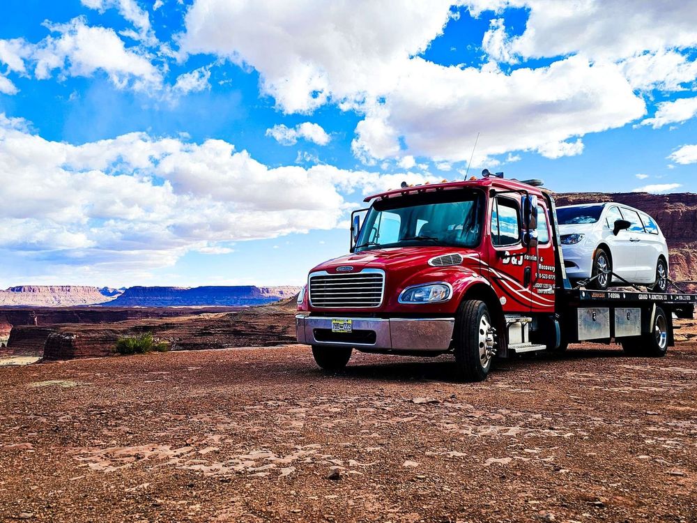 Red car towing a white SUV across a desert under a bright blue sky with clouds