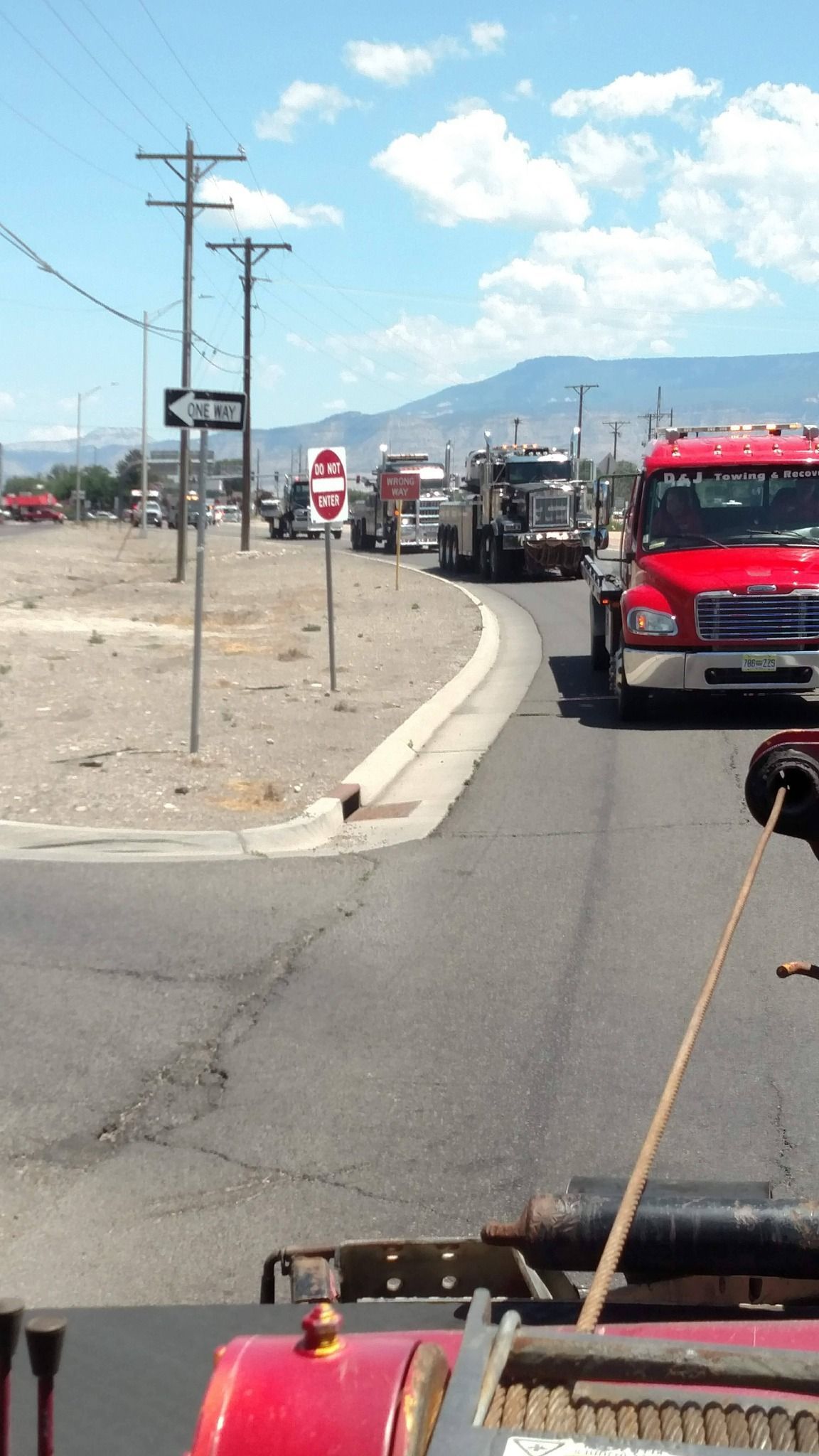 Fire trucks lined up along a roadside in a desert area under a bright blue sky.
