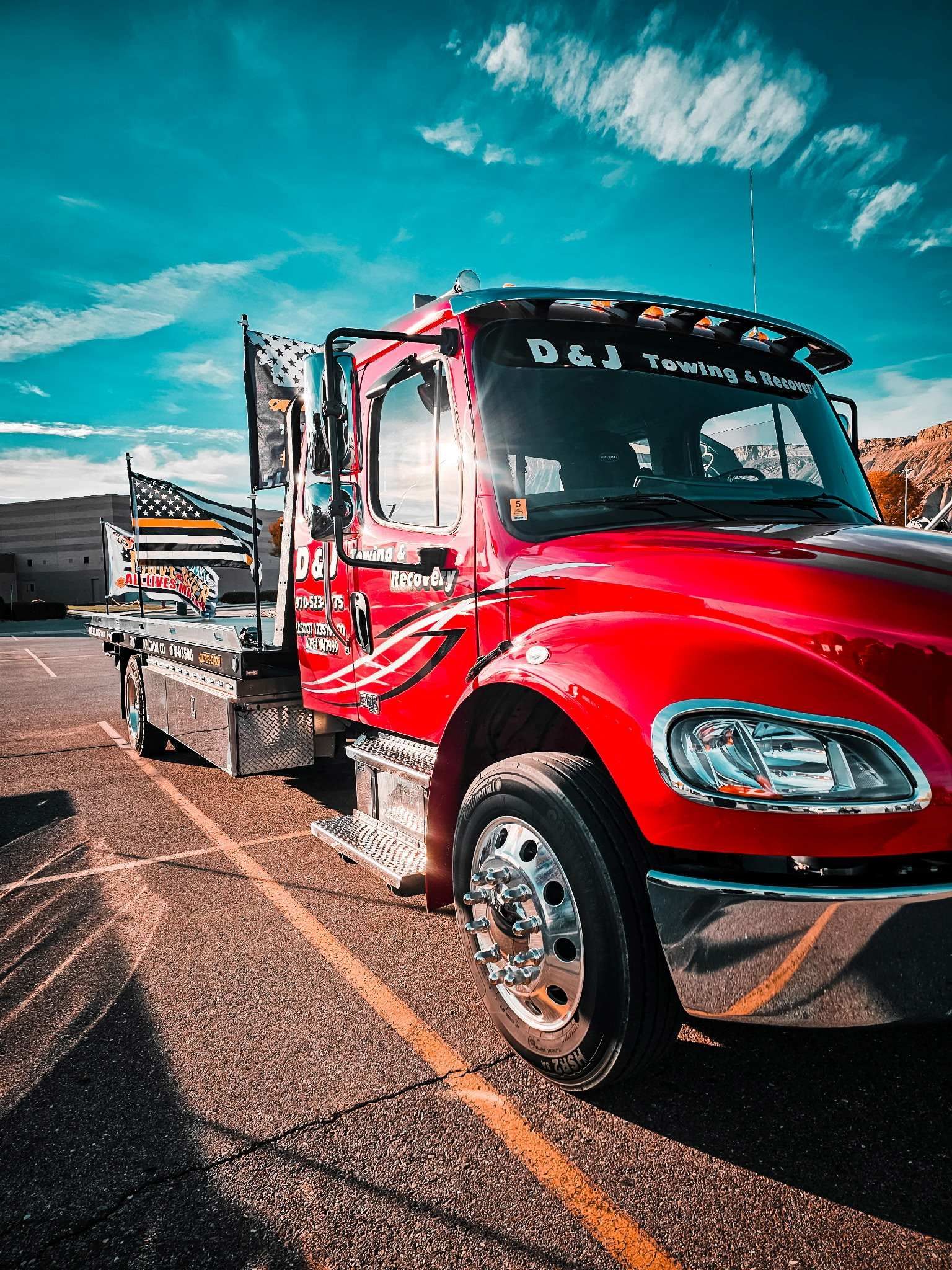 Red semi-truck parked on a road under a bright blue sky