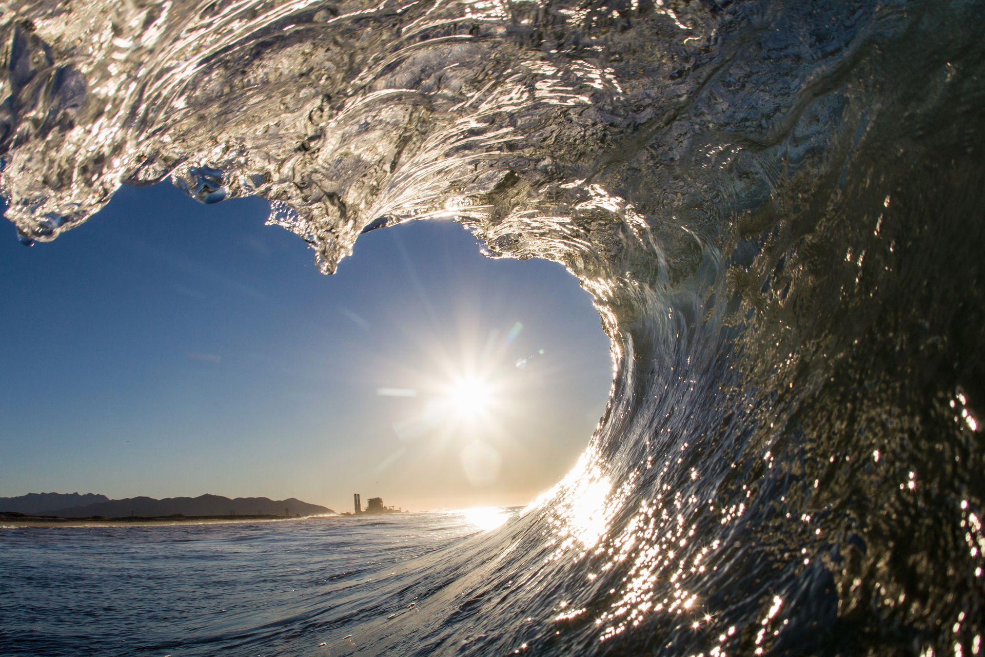 A wave in the ocean with the sun shining through it