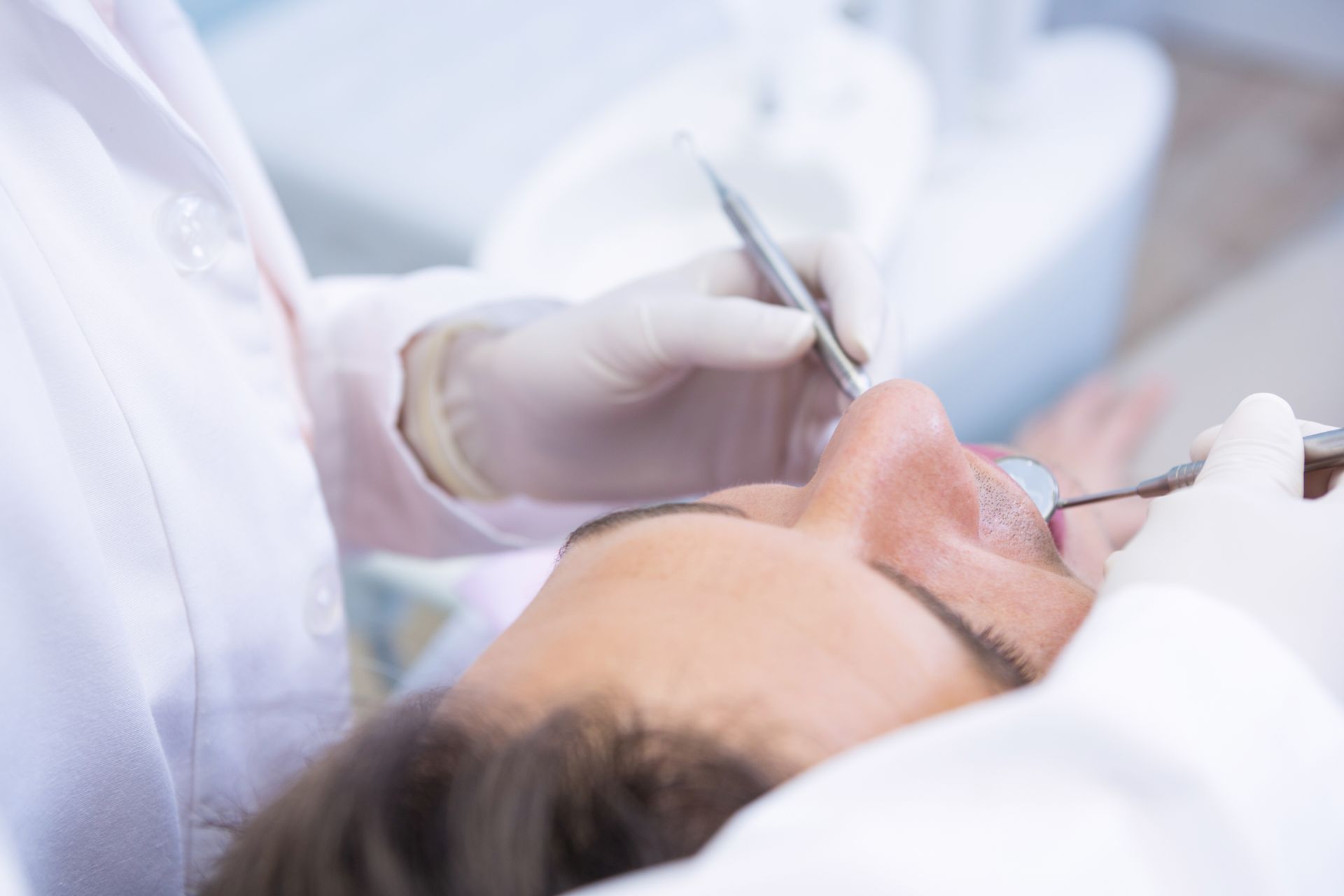 A dentist is examining a patient 's teeth in a dental office.