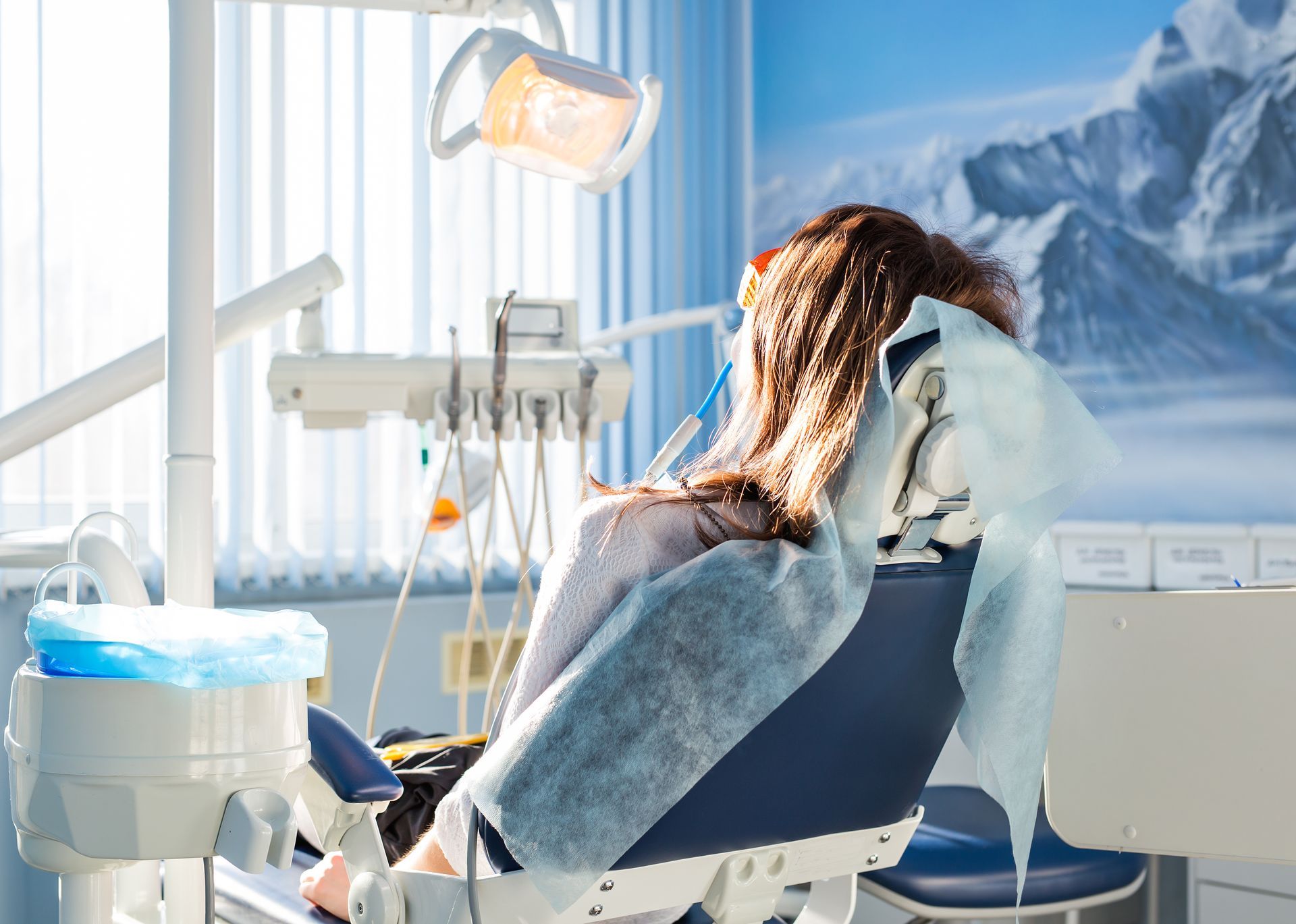 A woman is sitting in a dental chair in a dental office.