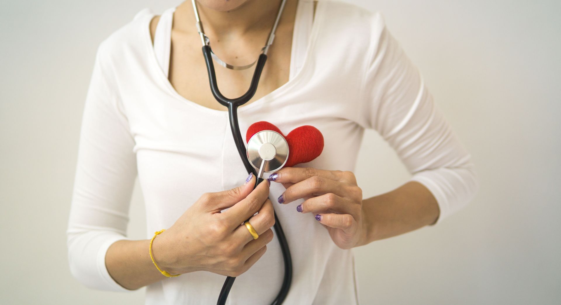 Person holding a stethoscope near a baby doll, suggesting a medical exam or training exercise