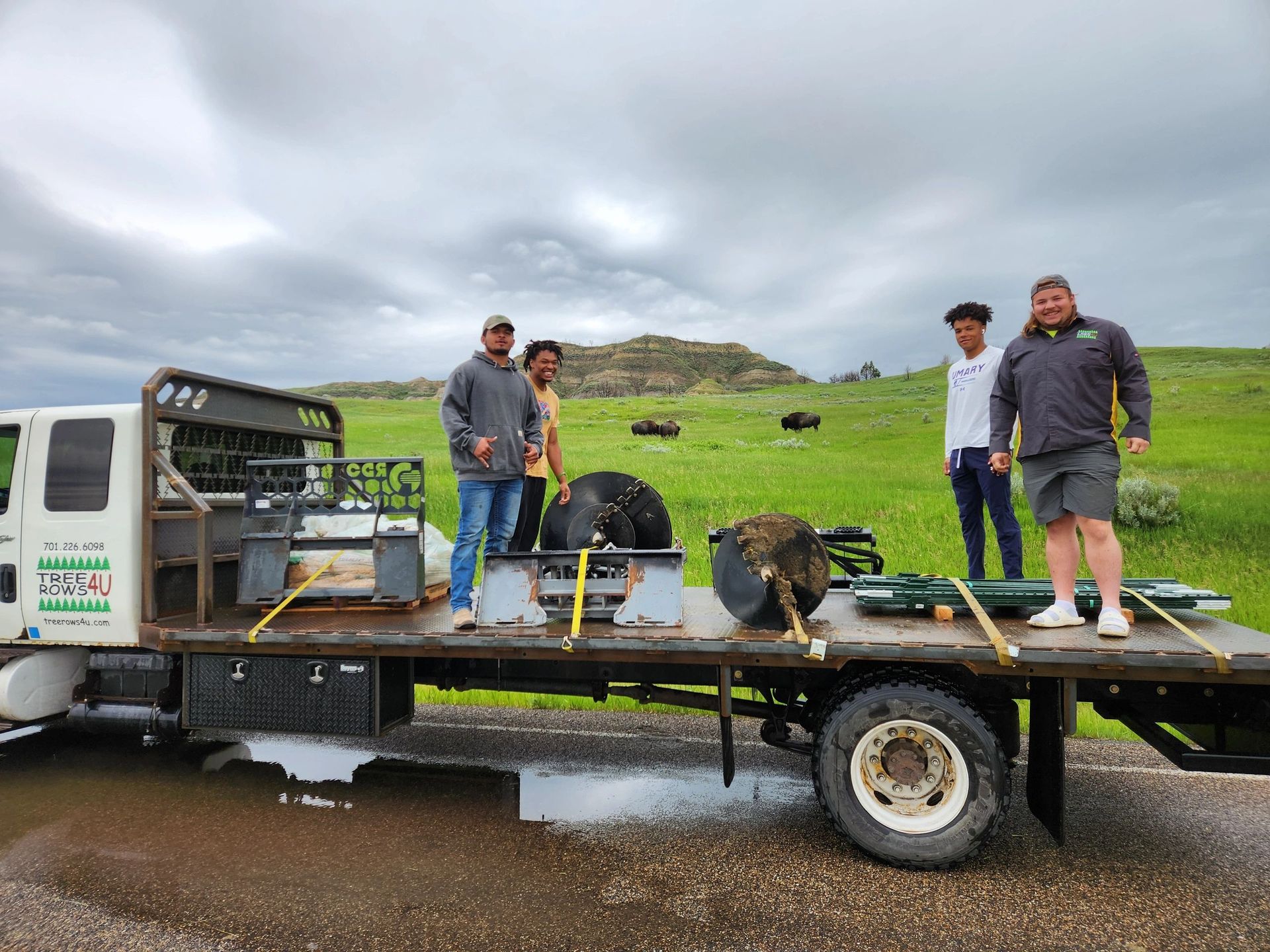 A group of people are standing on the back of a tow truck.