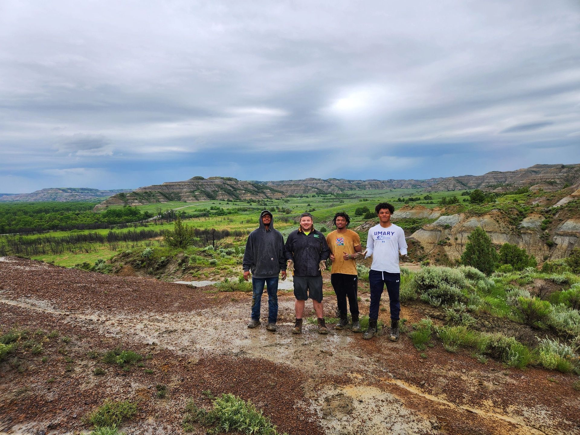 A group of people are standing on top of a dirt hill.