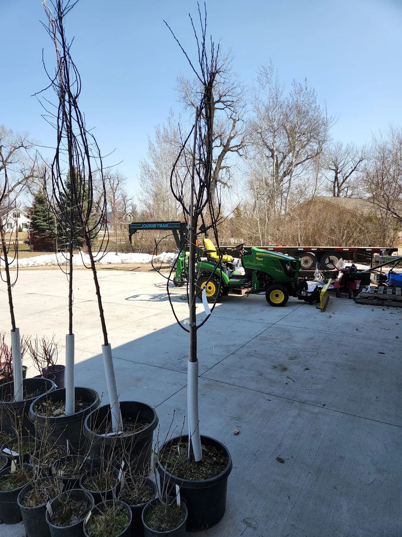 A john deere tractor is parked next to a bunch of potted plants