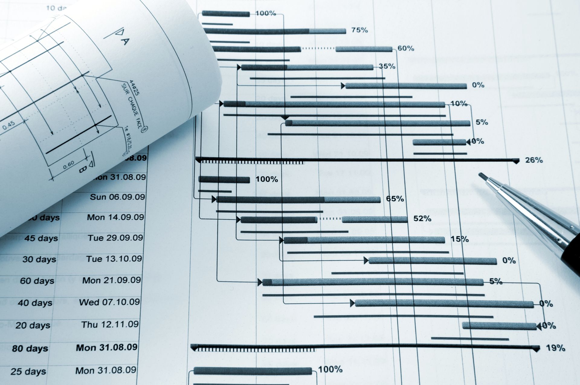A metallic pen rests on a project timeline gantt chart with technical engineering drawings in the background.