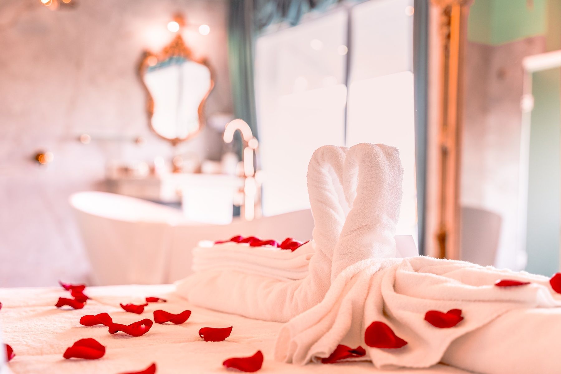 Uma cama decorada com toalhas e pétalas de rosas em um quarto de hotel.