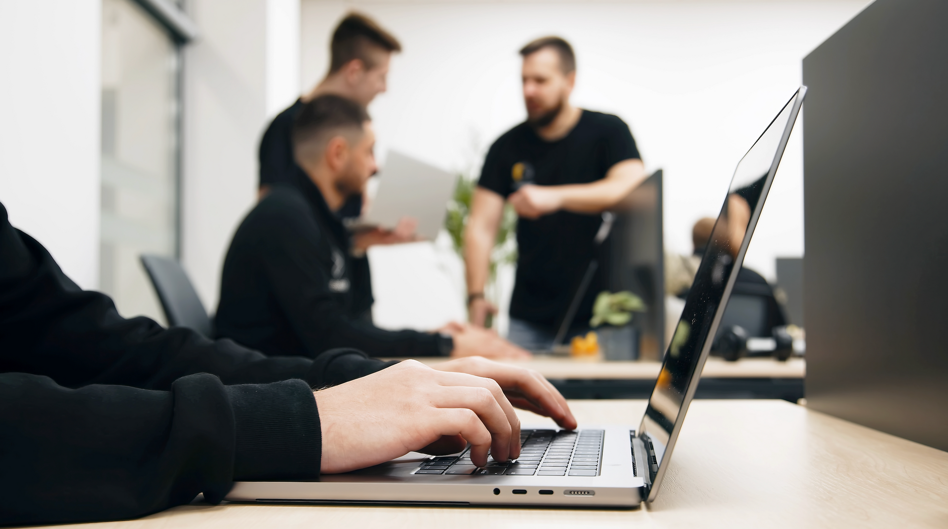 A group of men are sitting at a table using laptops.