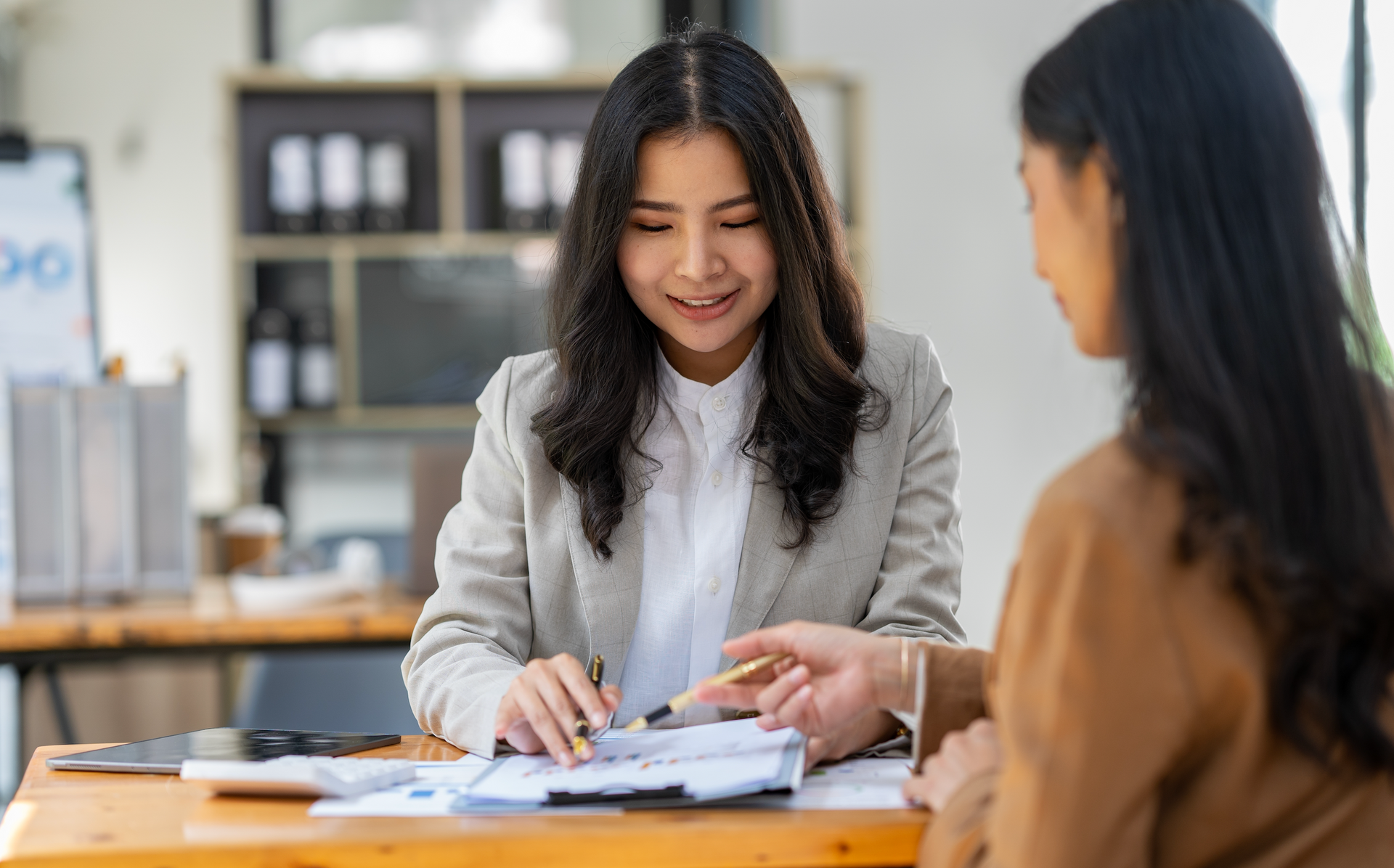 A woman is sitting at a table talking to another woman.