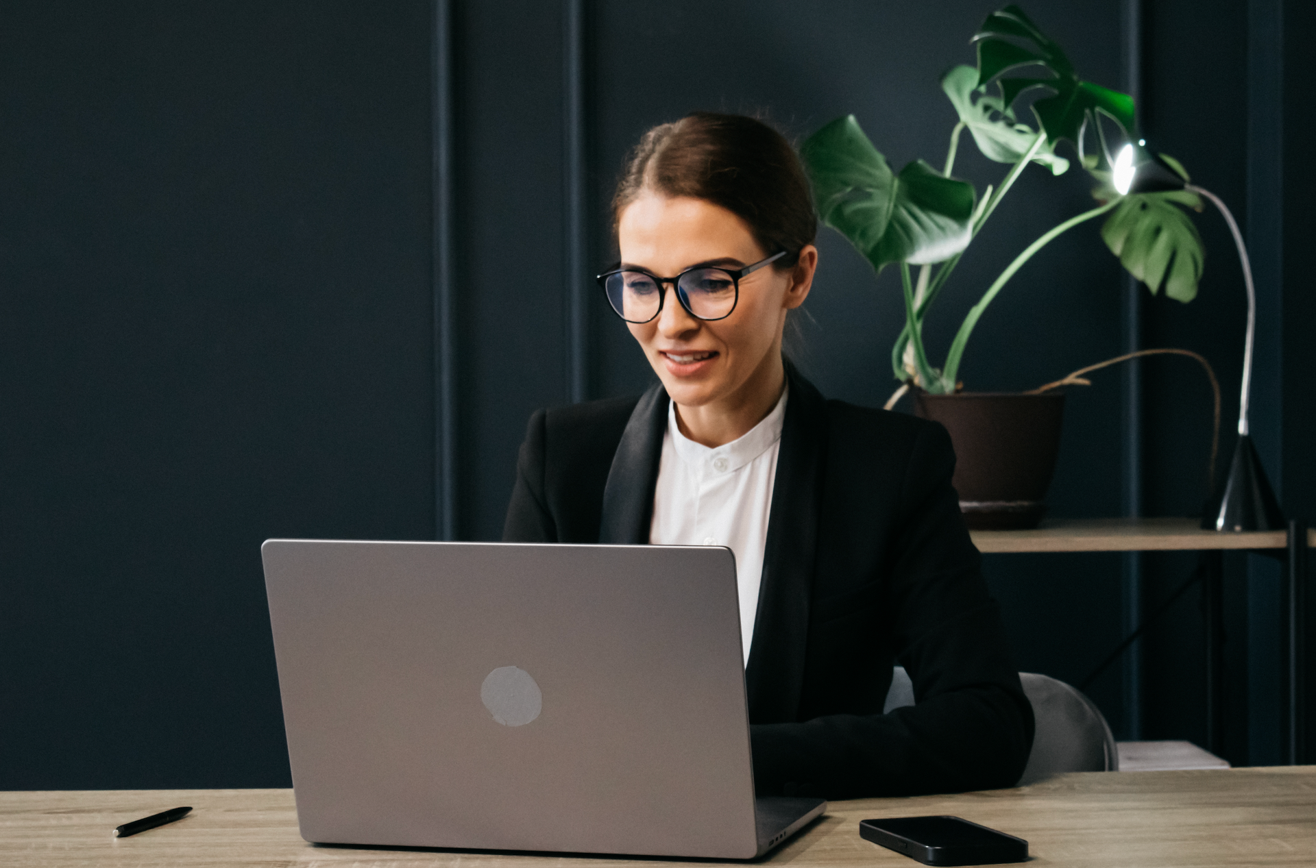 A woman is sitting at a desk using a laptop computer.