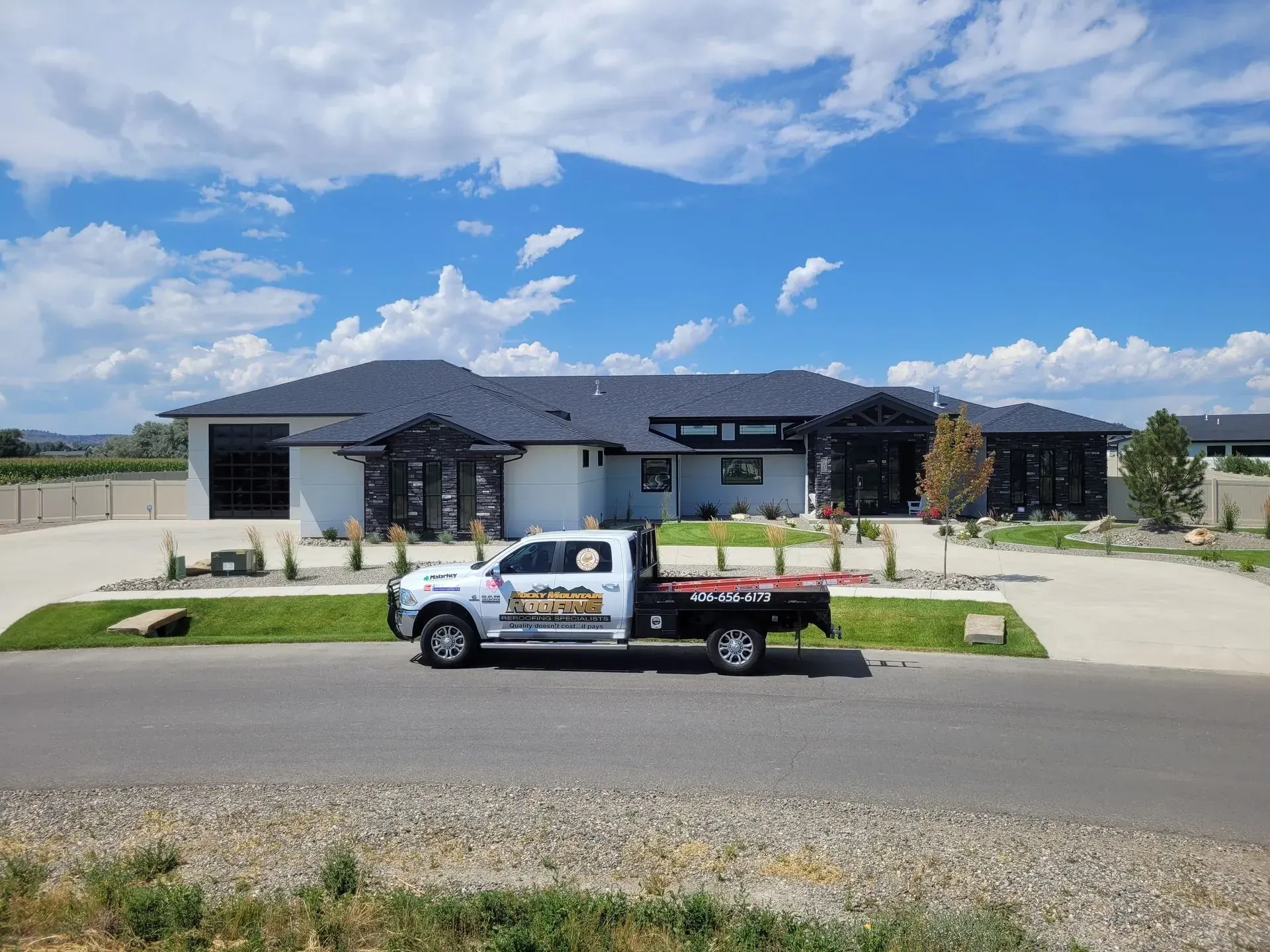 Work truck parked on a suburban street in front of a modern house under a blue sky.