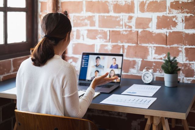 Business meeting with five people around a conference table, focused on a man speaking at the head of the table.