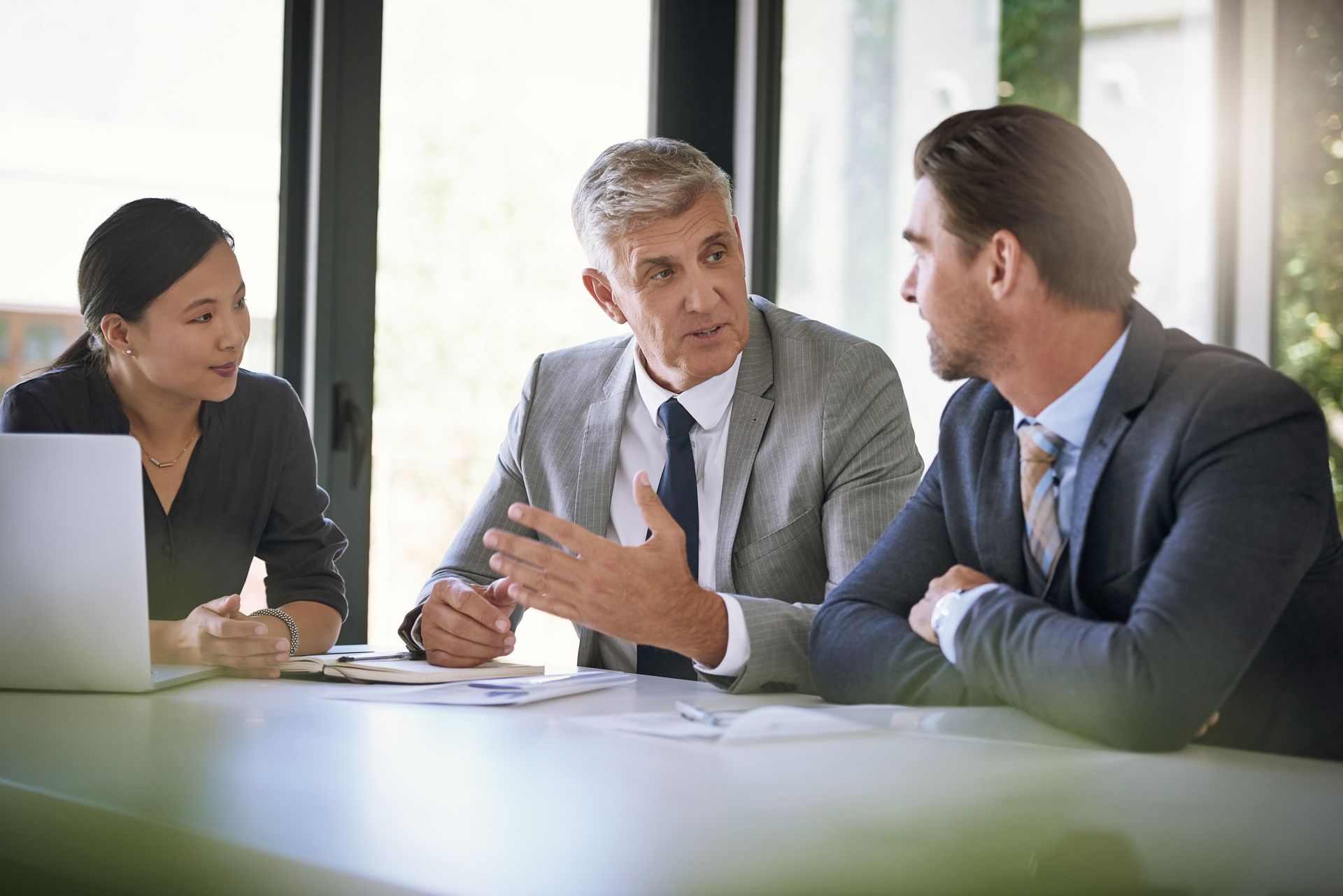 Three coworkers in a meeting, discussing over documents at a conference table