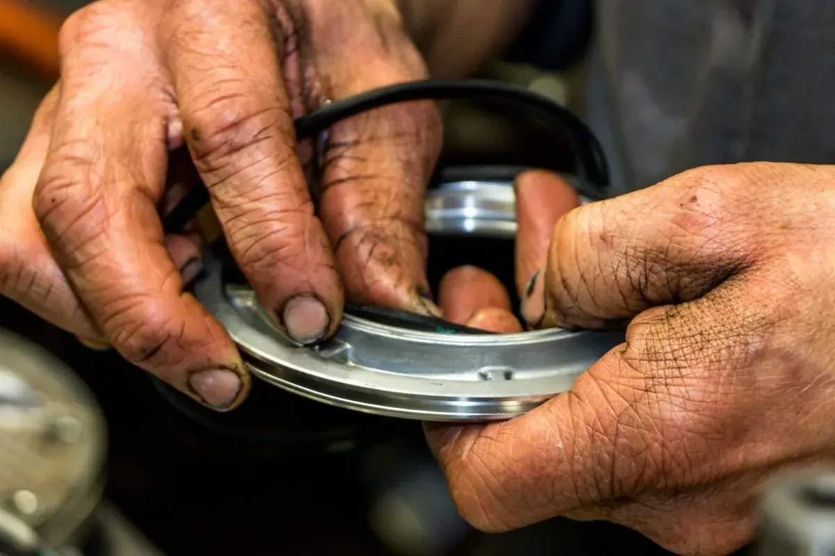 Hands repairing a metal watch with small tools on a workbench