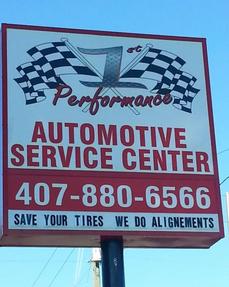 Performance Automotive Service Center sign with checkered flags, phone number, and tire alignment notice