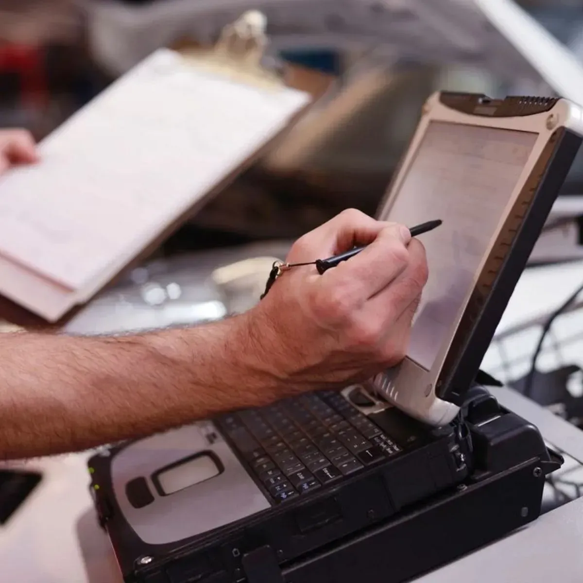 Hand using a stylus on a rugged tablet computer mounted in a case