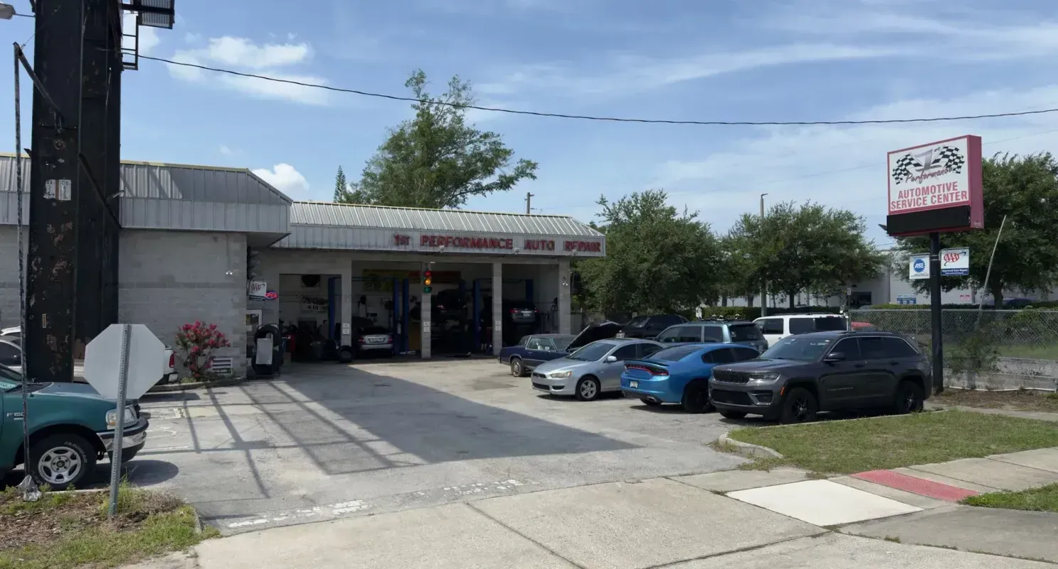 Small storefront with parked cars in front on a sunny street corner