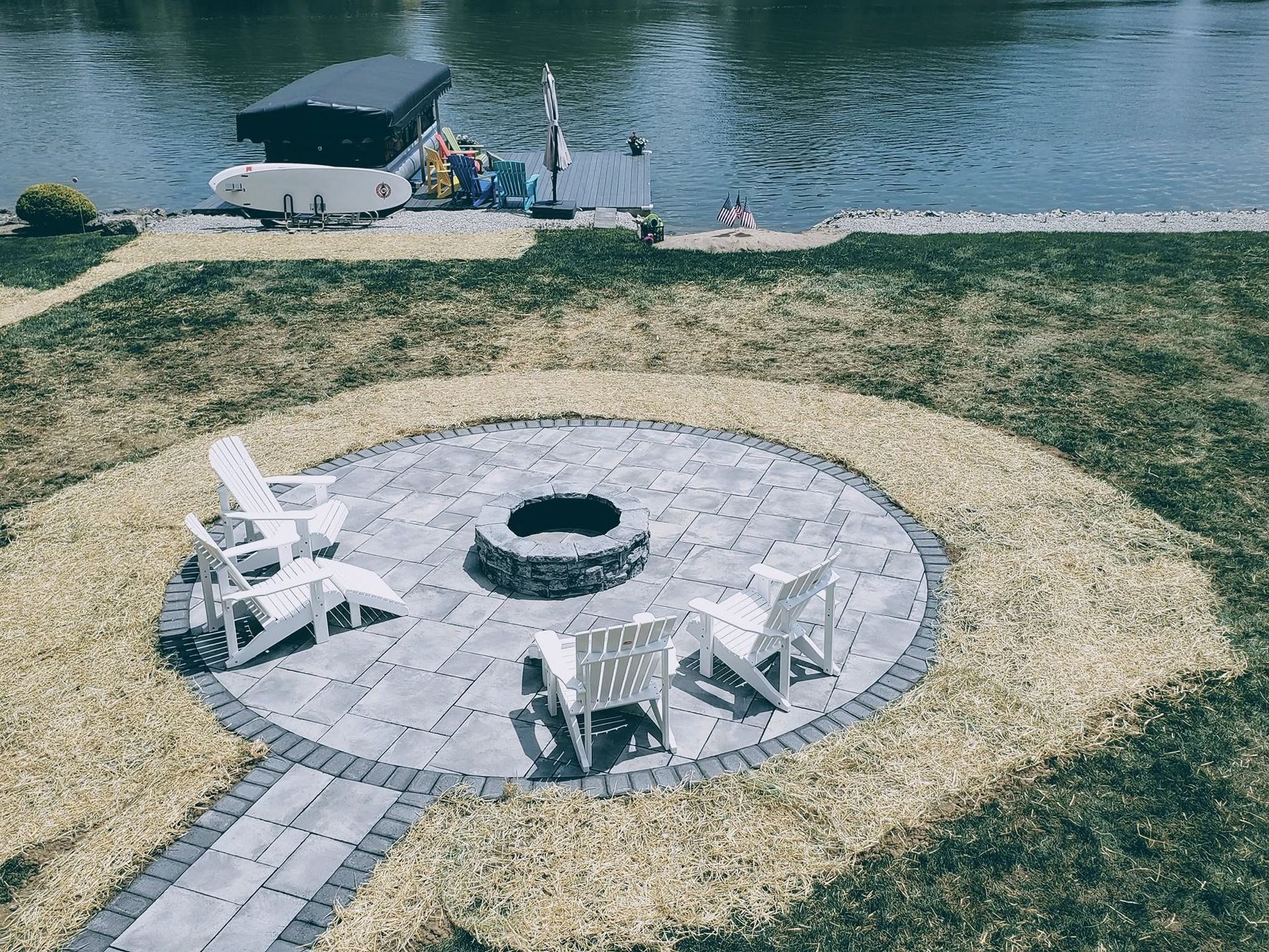 Lakeside backyard hardscape layout featuring a stone fire pit patio overlooking a private dock.