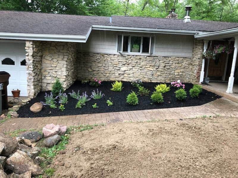 Freshly mulched front landscape bed with shrubs at a stone house in Indiana