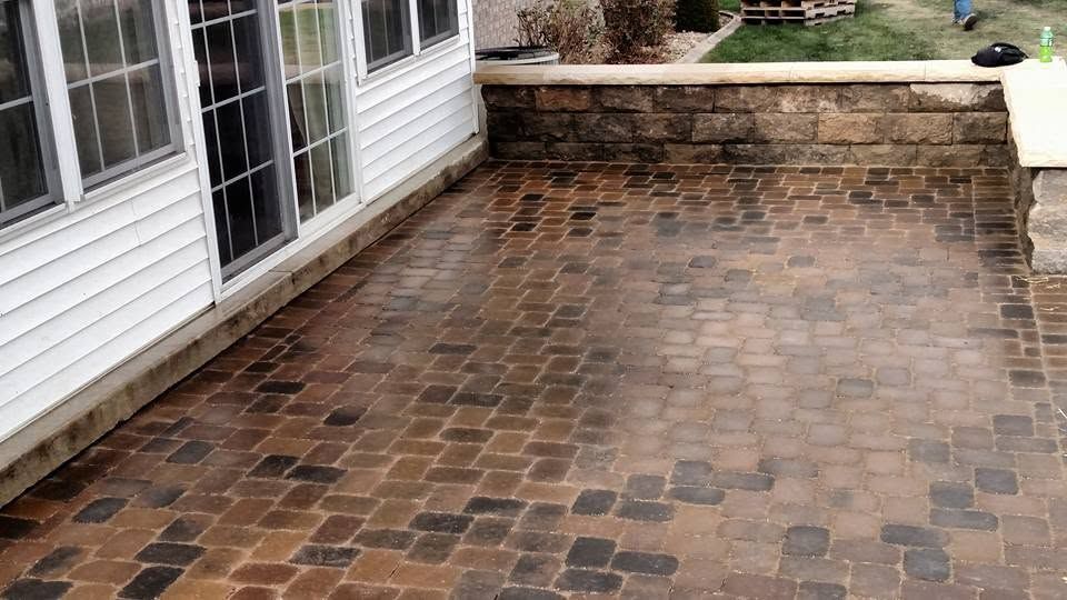 Brick paver patio with low stone retaining wall beside a residential home in Indiana