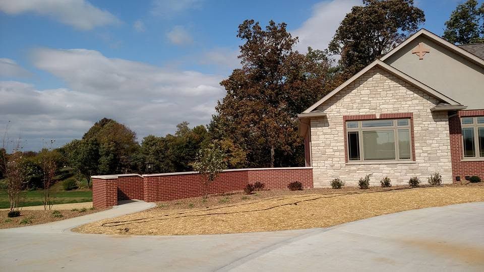Suburban house with brick accents, front lawn, and a driveway under a partly cloudy sky