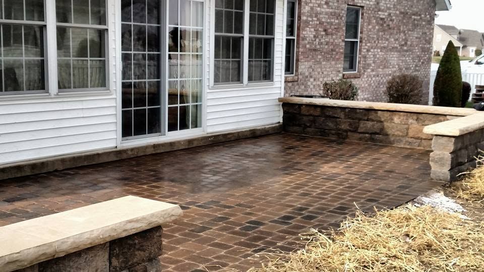 Dark brick paver patio outside a home's sliding glass doors and large windows