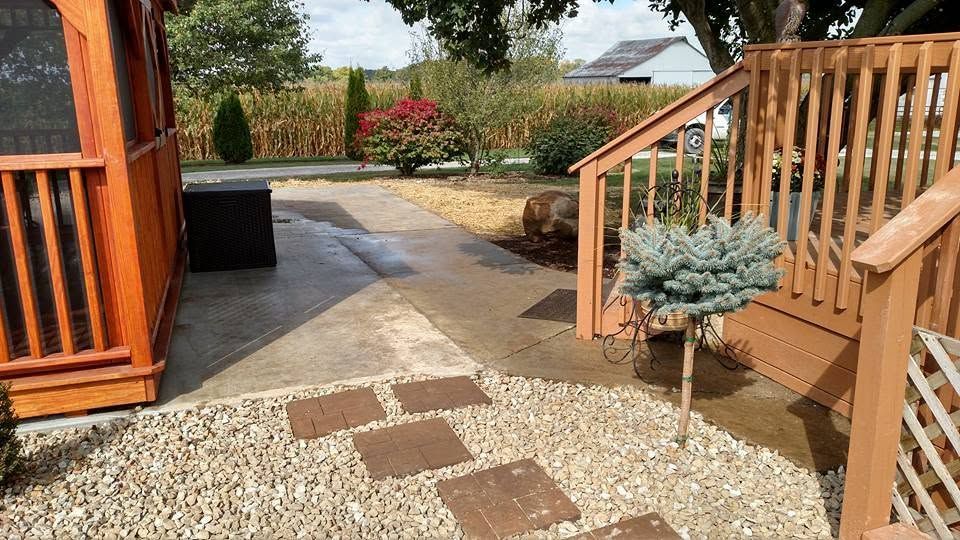 Concrete walkway and square stepping stones set in river rock gravel alongside a wooden deck staircase