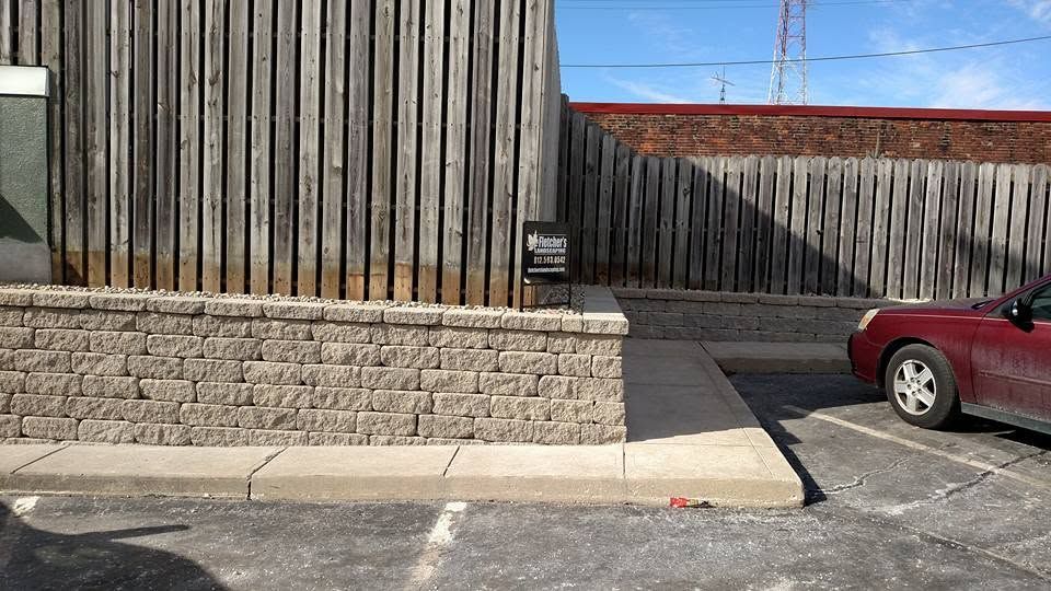 Stone retaining wall bordering a commercial parking area.