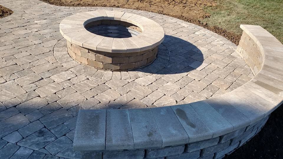 Paver patio featuring a built-in fire pit and curved seating wall.